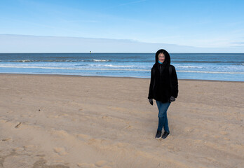 30 yo white woman standing on the beach with a winter coat, Knokke, Belgium