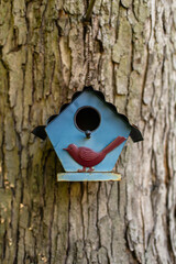 blue birdhouse with a red bird on a tree 