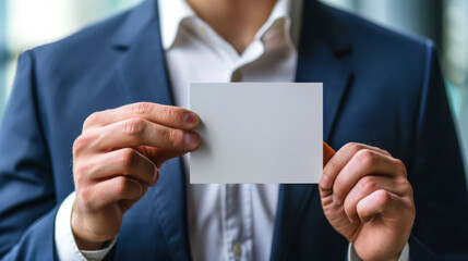 Fototapeta premium Businessman in suit holding blank card with both hands, close-up. Corporate identity and networking concept