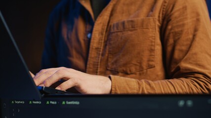 Programmer concentrating on writing complex binary code scripts on laptop terminal, close up shot....