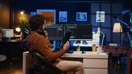 Software developer programming in home office, crosschecking lines of code between tablet and PC...