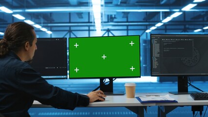 Software developer using green screen PC to do programming in server room providing computing...
