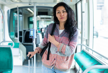 Asian woman with backpack sitting on seat inside tram