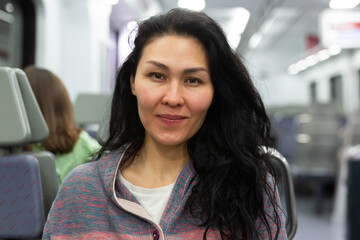 Smiling young adult woman in casual wear traveling by intercity train