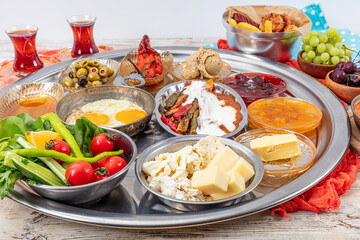 Traditional Turkish Breakfast Table (Serpme Kahvalti). Traditional Turkish village breakfast with fried eggs in a copper pan, menemen, honey clotted cream, cheese varieties on a wooden table.