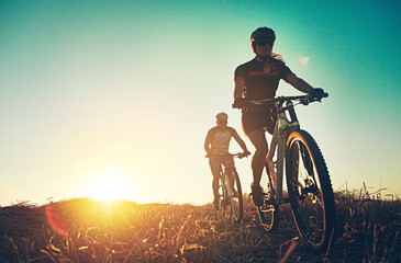 Sunset, people and friends on bicycle with adventure, race and exercise trail in nature together....