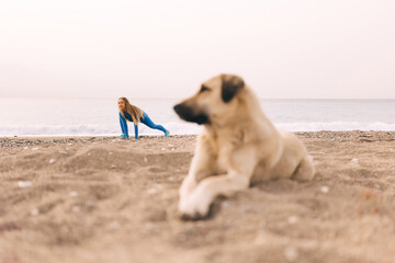 Young fitness woman in sports clothing stretching out on the beach in the morning.