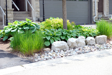 This small no grass front garden is low maintenance and features large rocks, river rock,...