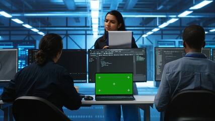 Multiethnic engineers working in high tech server hub, using green screen laptop and PCs to analyze...