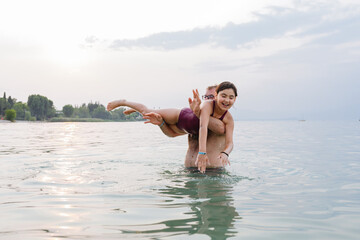 portrait of father standing in the water and holding in his arms daughter