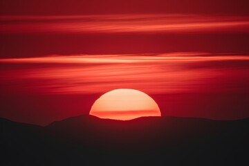 Obraz premium Vibrant sunset with reds, oranges, and silhouetted mountains, creating a serene atmosphere