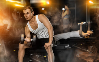 Sportive young man lifting heavy dumbbell in sports hall during crossfit workout