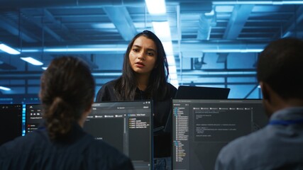 Supervisor in server hub managing multiracial team of programmers looking for equipment...
