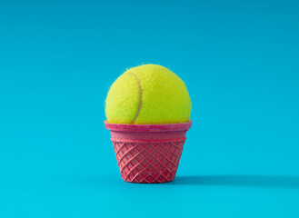 Pink ice cream cone with tennis ball on light blue background. Creative sport or food concept. Minimal surreal banner. Trendy ice cream and tennis ball idea.