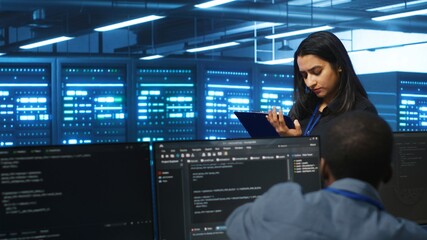 Manager overseeing server room, walking around with checklist on notepad, troubleshooting hardware....