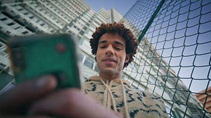 Happy zoomer chatting phone surrounded by cityscape closeup. Man reading message