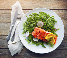 Food, fish and healthy salad with nutrition for sinner, lunch plate and lose weight with pescatarian diet. Salmon, rocket and plant leaves or herbs for digestion with fine dining on wood background