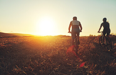 Sunset sky, people and friends in bicycle race with grass, exercise and adventure trail in nature...