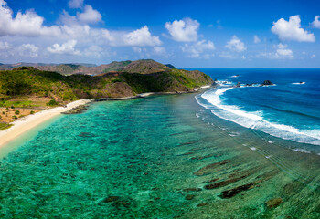 Aerial view of a sandy tropical beach and coral reef surrounded by hills (Tampah)