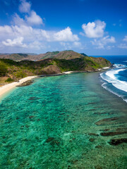 Aerial view of a sandy tropical beach and coral reef surrounded by hills (Tampah)