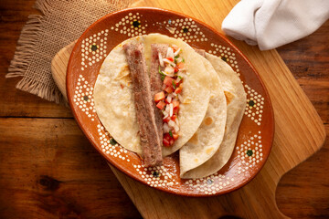 Arrachera Tacos. Marinated beef steak served in a wheat tortilla on a mexican clay plate. Street food from Mexico, traditionally accompanied with cilantro, onion and spicy sauce or guacamole.