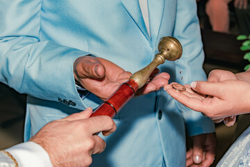 detail of the hands of a priest blessing the rings of a couple with holy water