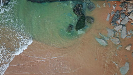 Turquoise ocean waves caressing sandy shore top view. Foamy water meeting beach