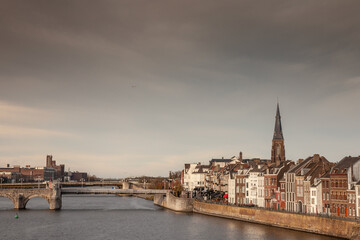 Naklejka premium Panorama of Maastricht Waterfront on the Meuse Maas river with a focus on the Sint Martniuskerk, a catholic church and typical dutch architecture houses in the netherlands.