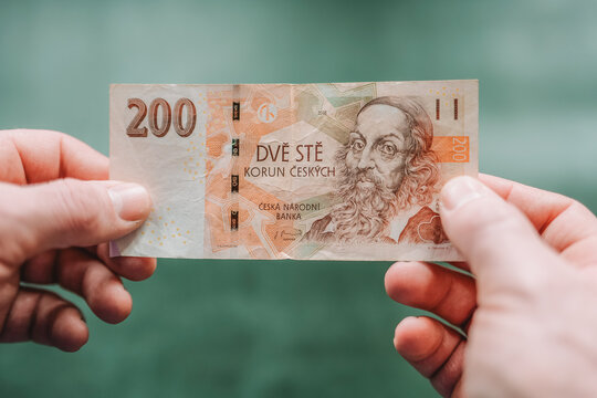  Two hundred Czech crowns close-up. Hands count Czech money.currency of the Czech Republic is the Czech koruna.