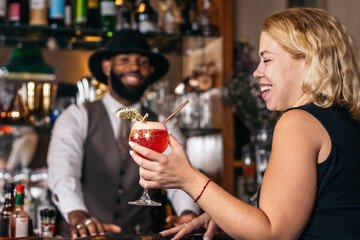 stylish black bartender offering a customer a cocktail