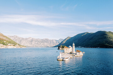 Motorboat is moored opposite the lighthouse on the island of Gospa od Skrpjela. Bay of Kotor,...