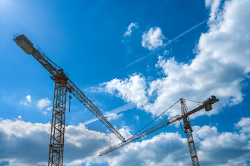 Construction cranes on a background of blue sky. Construction concept.