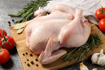 Fresh raw chicken with spices and vegetables on grey table