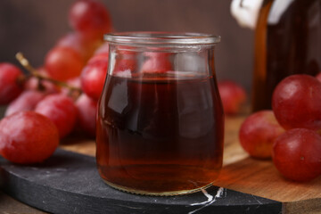 Wine vinegar in glass jar and grapes on table