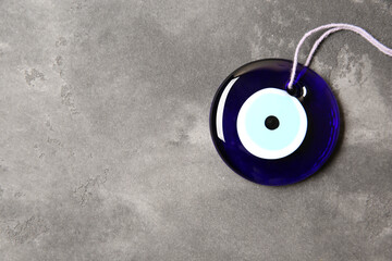 Evil eye amulet on grey table, top view. Space for text