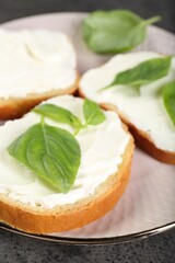 Delicious sandwiches with cream cheese and basil leaves on grey table, closeup