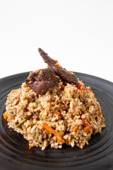 nasi kebuli, indonesian food with brown rice spicy and goat meat on black plate close up white background