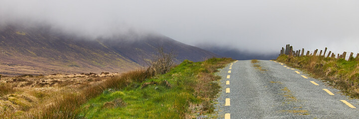 Irish road leading into the mountains covered in clouds