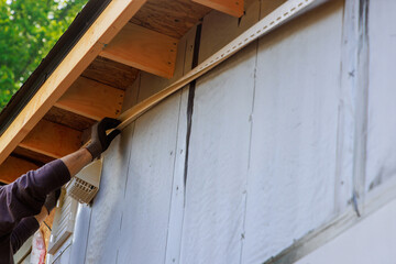 During construction of house, craftsman nails J-channel vinyl trim before installing it for siding