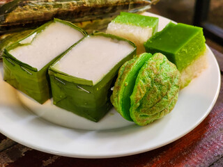 Kuih Seri Muka and Kuih Cara are on a white plate. These are delicious and popular Malaysian traditional snacks. Close-up food photo.