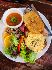 Delicious English breakfast on a white plate served on a brown wooden table
