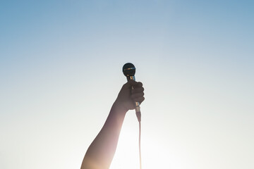 man hand holding a microphone outdoors with sunlight reflects