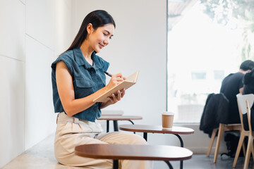 A woman is sitting at a table with a book in front of her. She is smiling and she is enjoying...