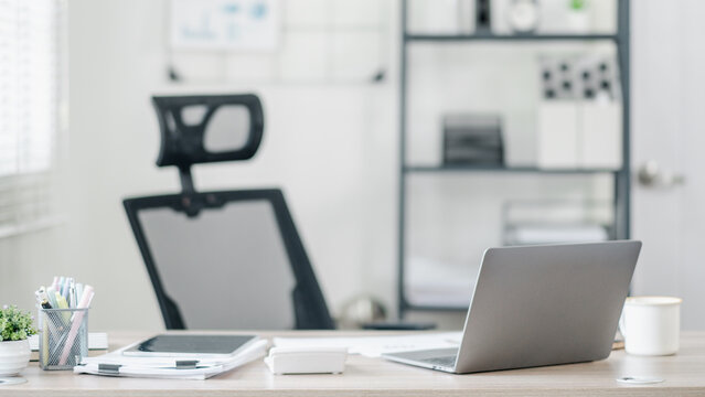 A clean and organized modern office workspace featuring a laptop, chair, and various office supplies in a bright, minimalist setting.