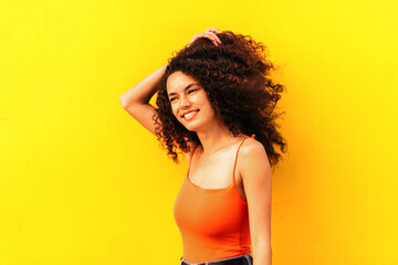 beautiful afro woman looking aside portrait leaning on a yellow wall