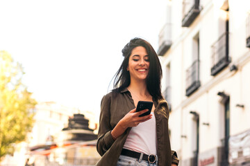 stylish young woman walking and using her mobile
