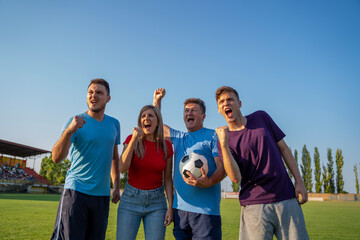 Group of people, man and his sons and daughter on football field yelling and cheering , stands behind them, real-life experience of soccer match concept   © phoenix021