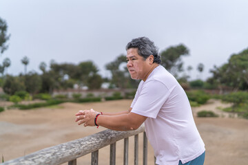 Sad man with vitiligo leaning on rail in a park