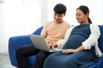 Fototapeta premium pregnant woman with her husband doing online shopping from laptop computer at home