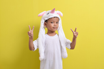 Asian little boy posing wearing cute character hat on yellow background. Portrait of a cute Asian boy